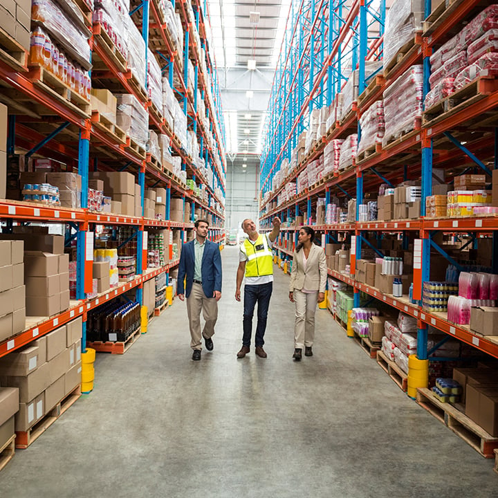 Warehouse employee giving two other people a tour of warehouse