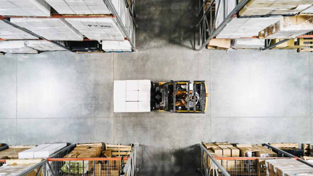 Birds eye view of a forklift driving through a warehouse aisle 