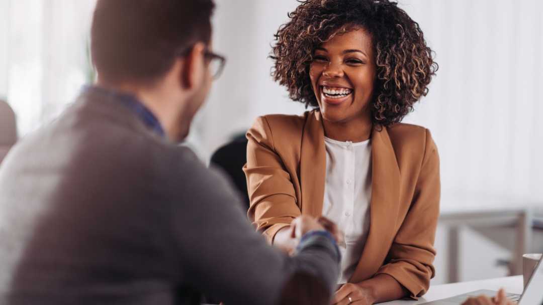 Man and woman shaking hands across from each other at a table