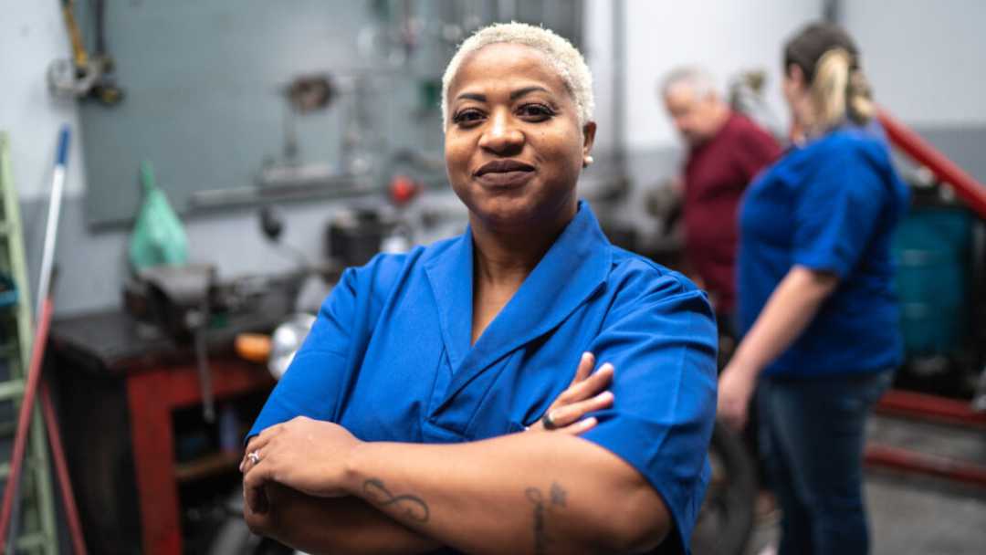 Manufacturing worker smiling into a camera with arms crossed