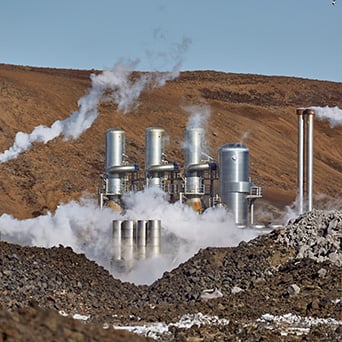 smoking pipes in a power plant surrounded by gravel and mountains