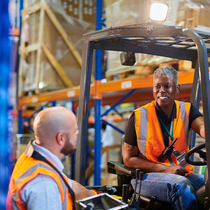 Forklift driver talking to warehouse floorman