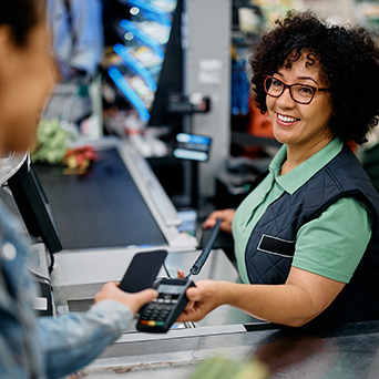 someone using their phone to pay a cashier holding a card reader up to them