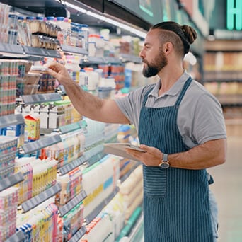 worker wearing an apron stocking shelves at a store