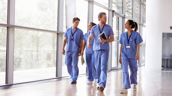 Nurses in scrubs walking together in hospital hallway.